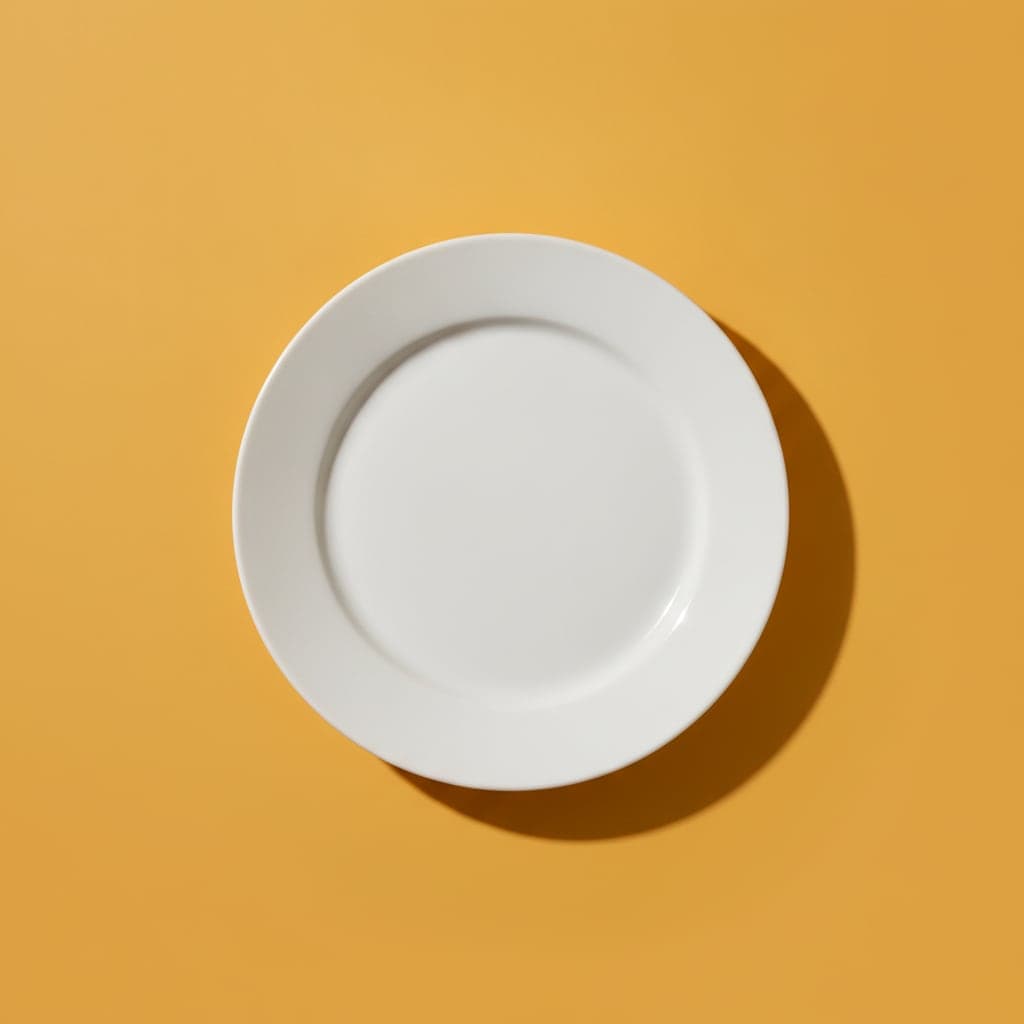 A plain empty white plate on an amber background